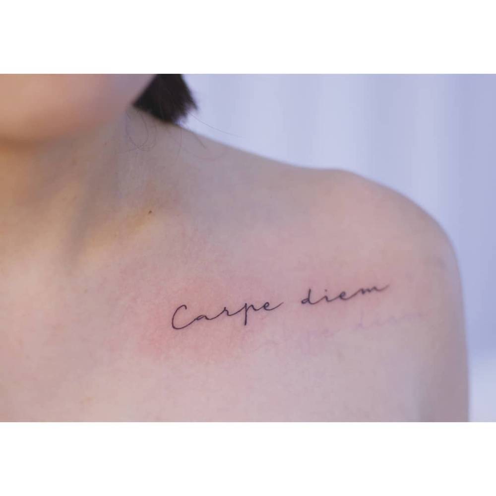 "Carpe diem" lettering tattoo in handwritten font.