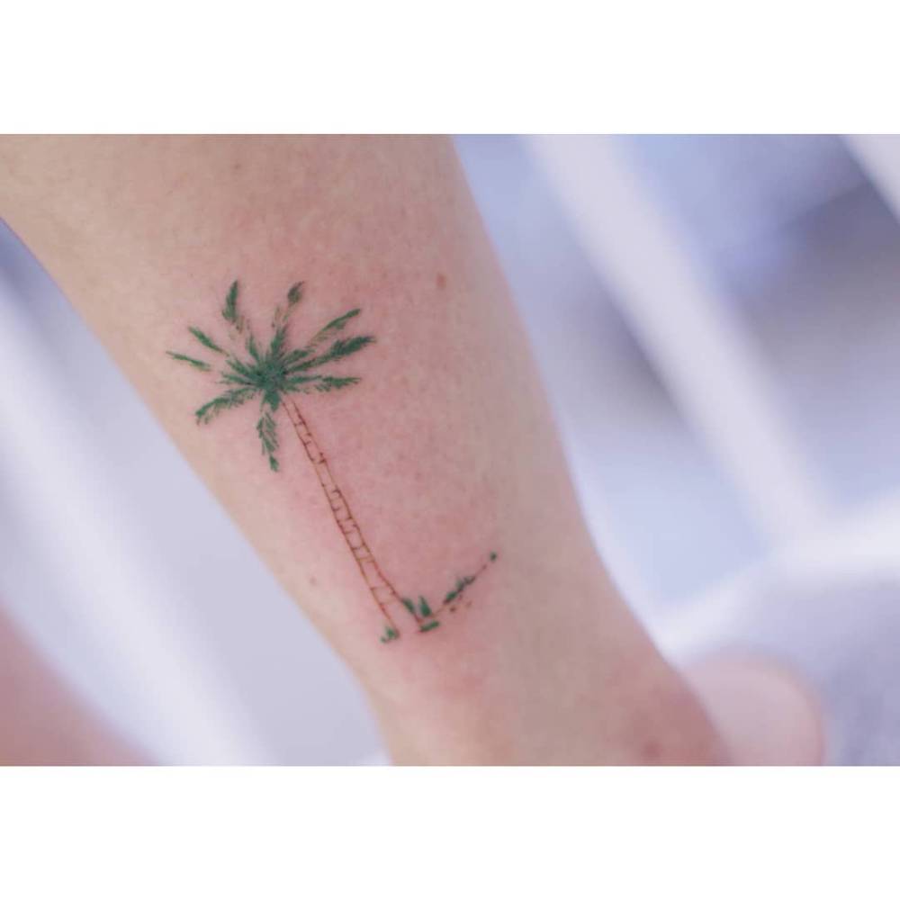 Watercolor style palm tree tattoo placed on the ankle.