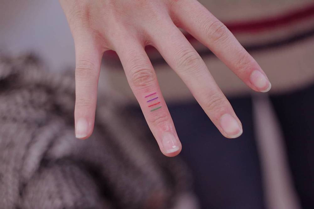 Minimalistic colorful lines tattooed on the finger.