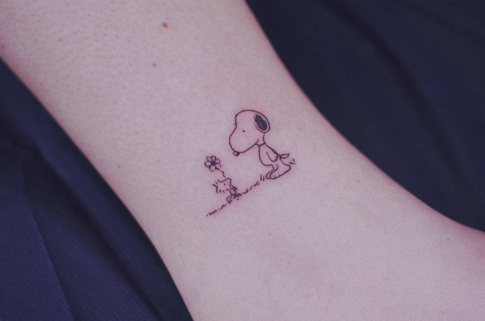 Woodstock and Snoopy tattoo in cartoon style located on the ankle.