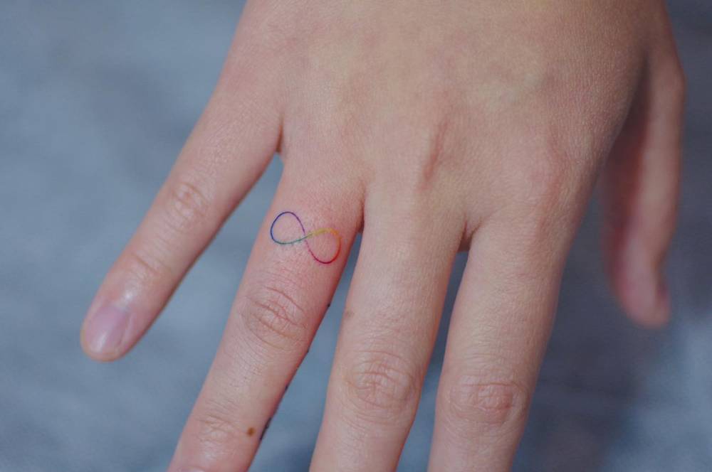 Spectrum infinity symbol tattoo located on the finger.