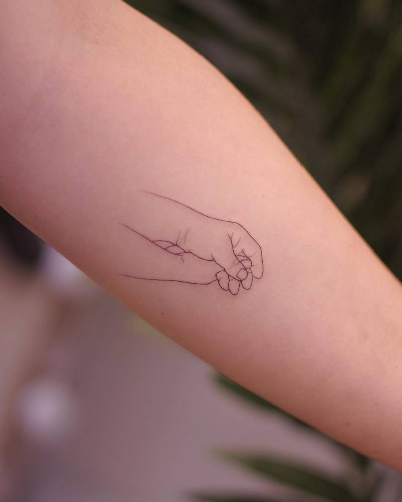 Holding hands tattoo in fine line style placed on the inner forearm.