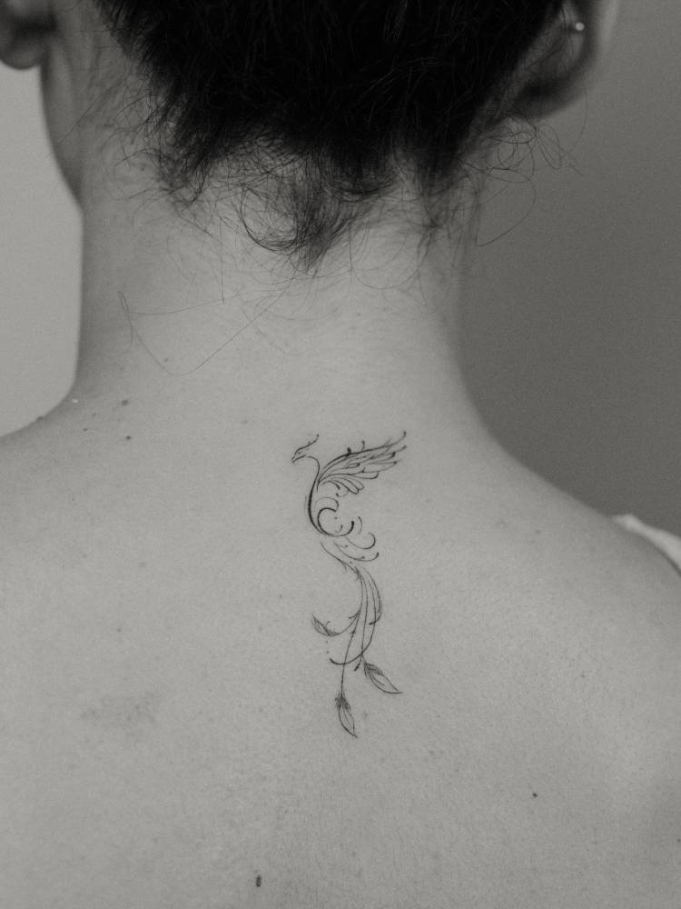 Phoenix tattoo in fine line style placed on the upper back.
