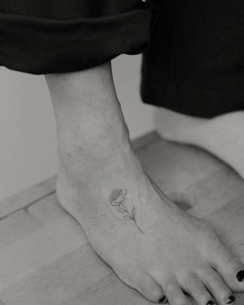 Rose tattoo in fine line style located on the foot.