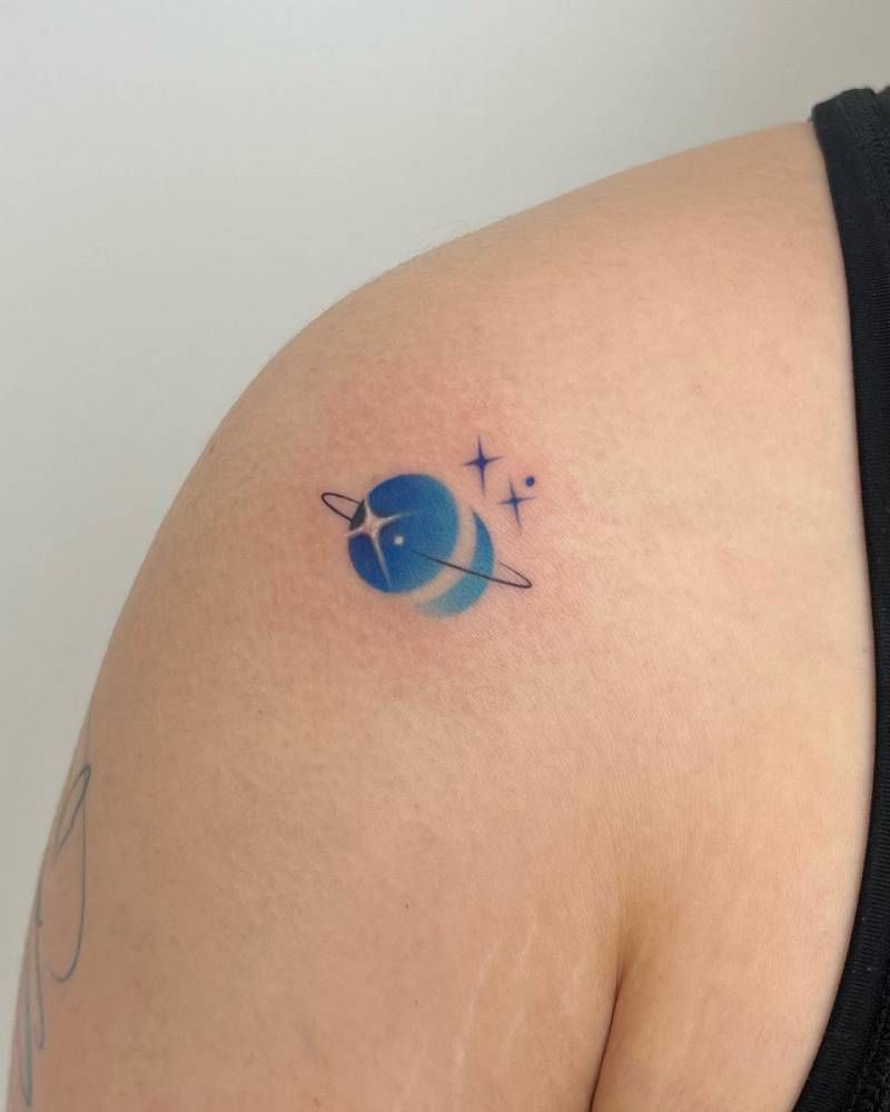 Watercolor style Saturn and moon tattoo located on the shoulder.