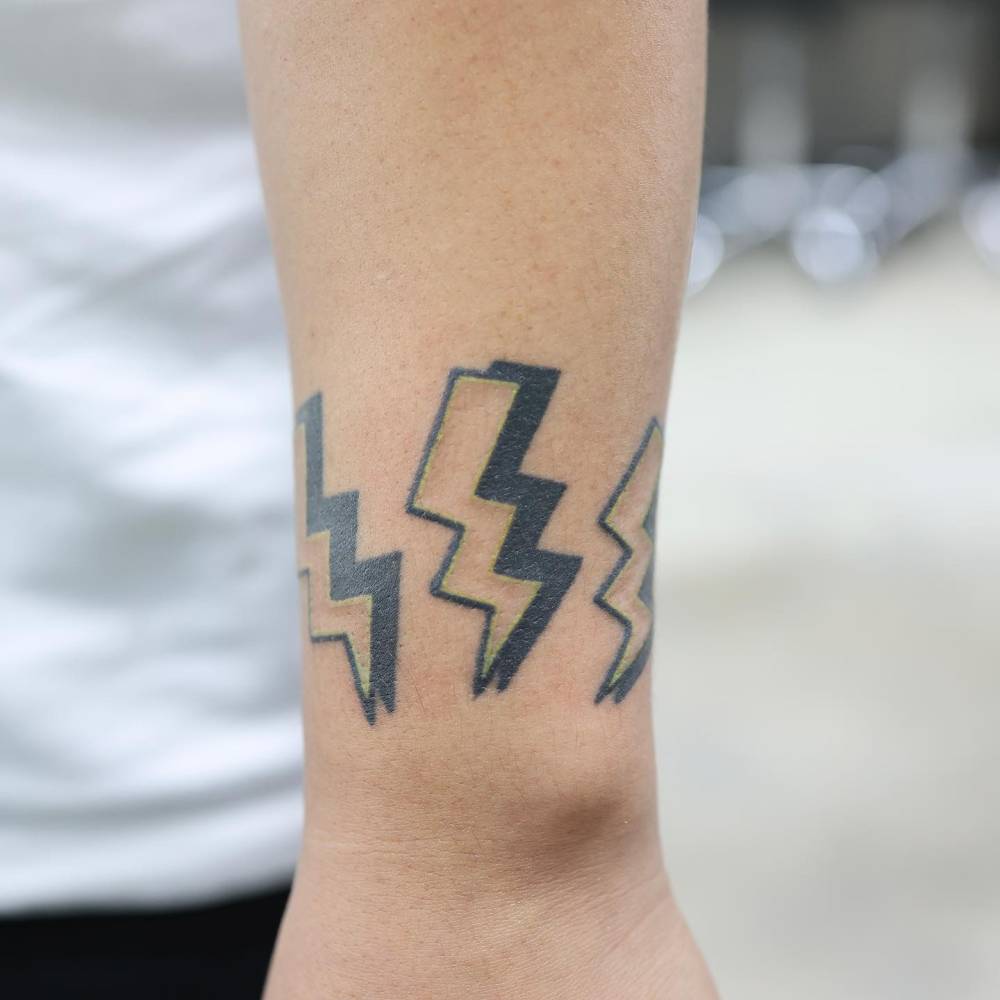 Illustrative style lightning bolts tattoo located on the tricep.