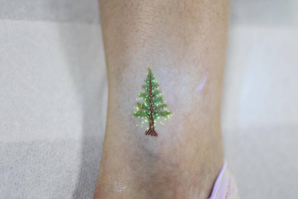 UV ink Christmas tree tattoo in illustrative style.