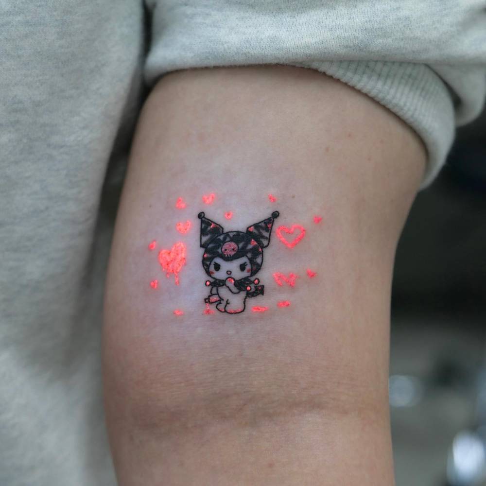 UV ink Kuromi tattoo in cartoon style located on the bicep.