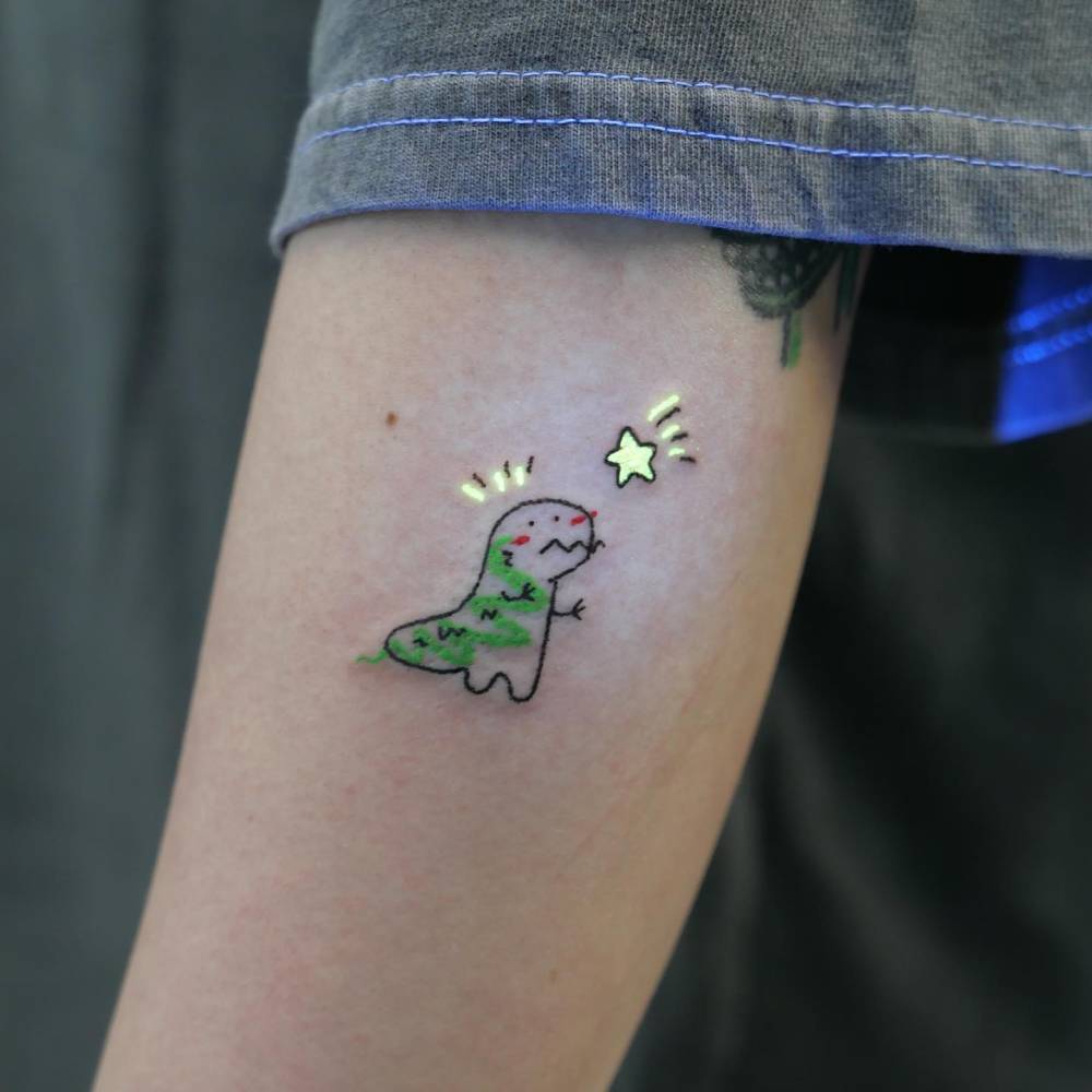 T-Rex tattoo in cartoon style located on the forearm.