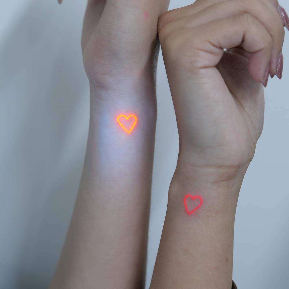Matching UV ink hearts tattoo for best friends.