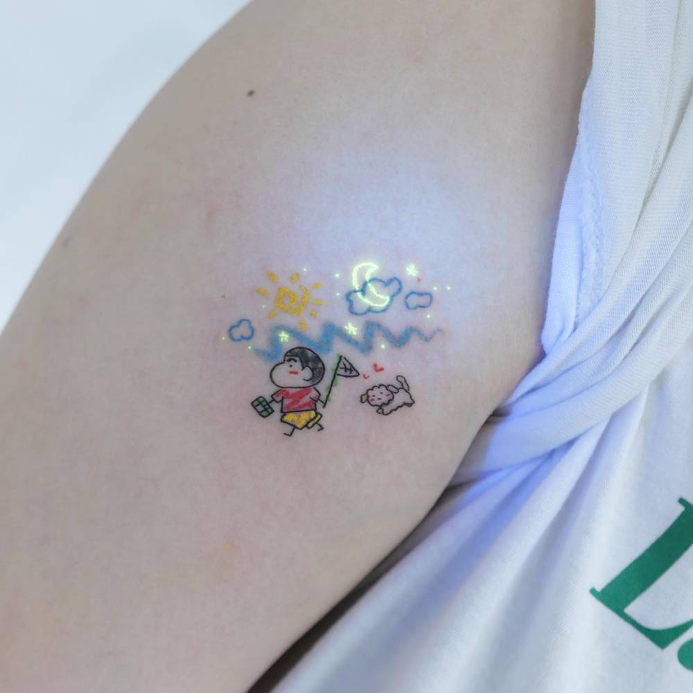 Cartoon style Shin-Chan tattoo placed on the upper arm.
