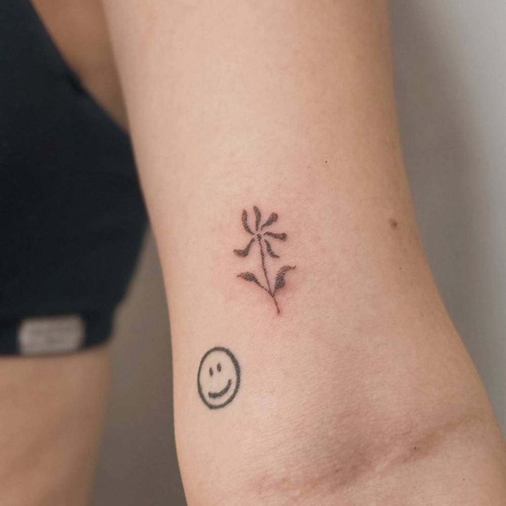 Dotwork style little flower tattoo located on the bicep.