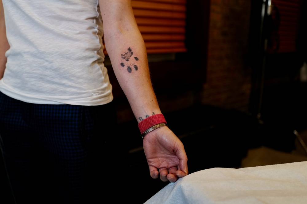 Water color style do paw print tattoo located on the inner forearm.