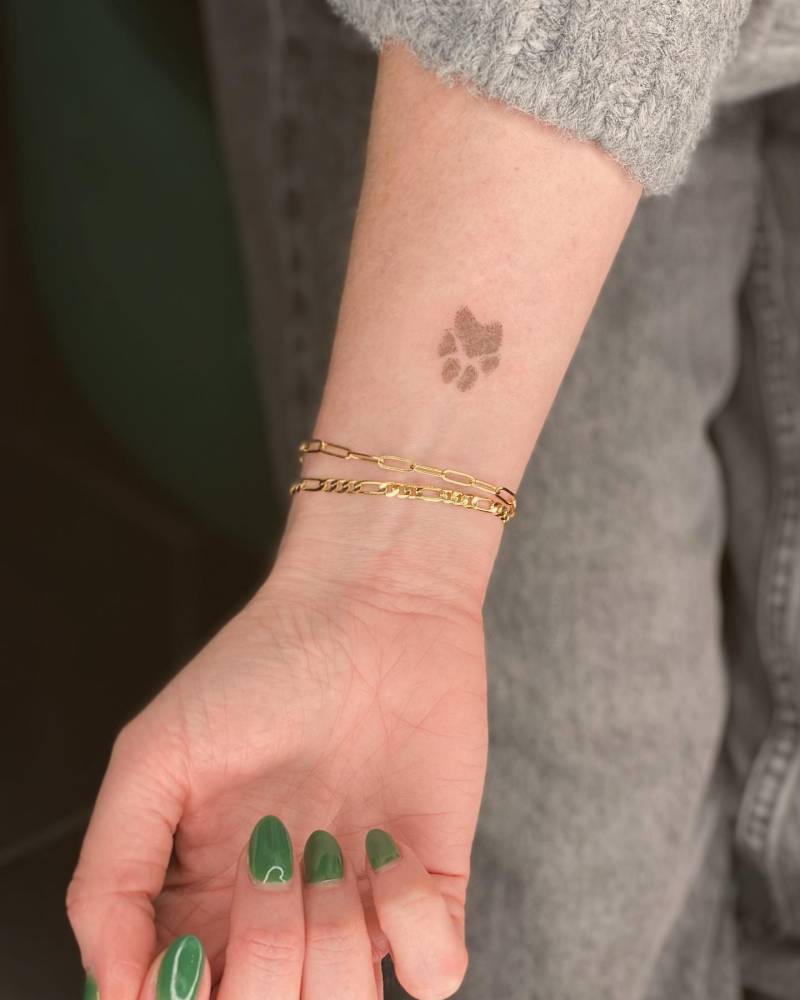 Little paw print tattoo placed on the wrist.