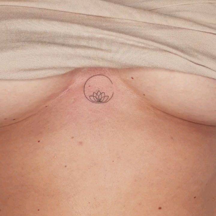 Minimalist lotus flower and circle tattoo on the sternum.