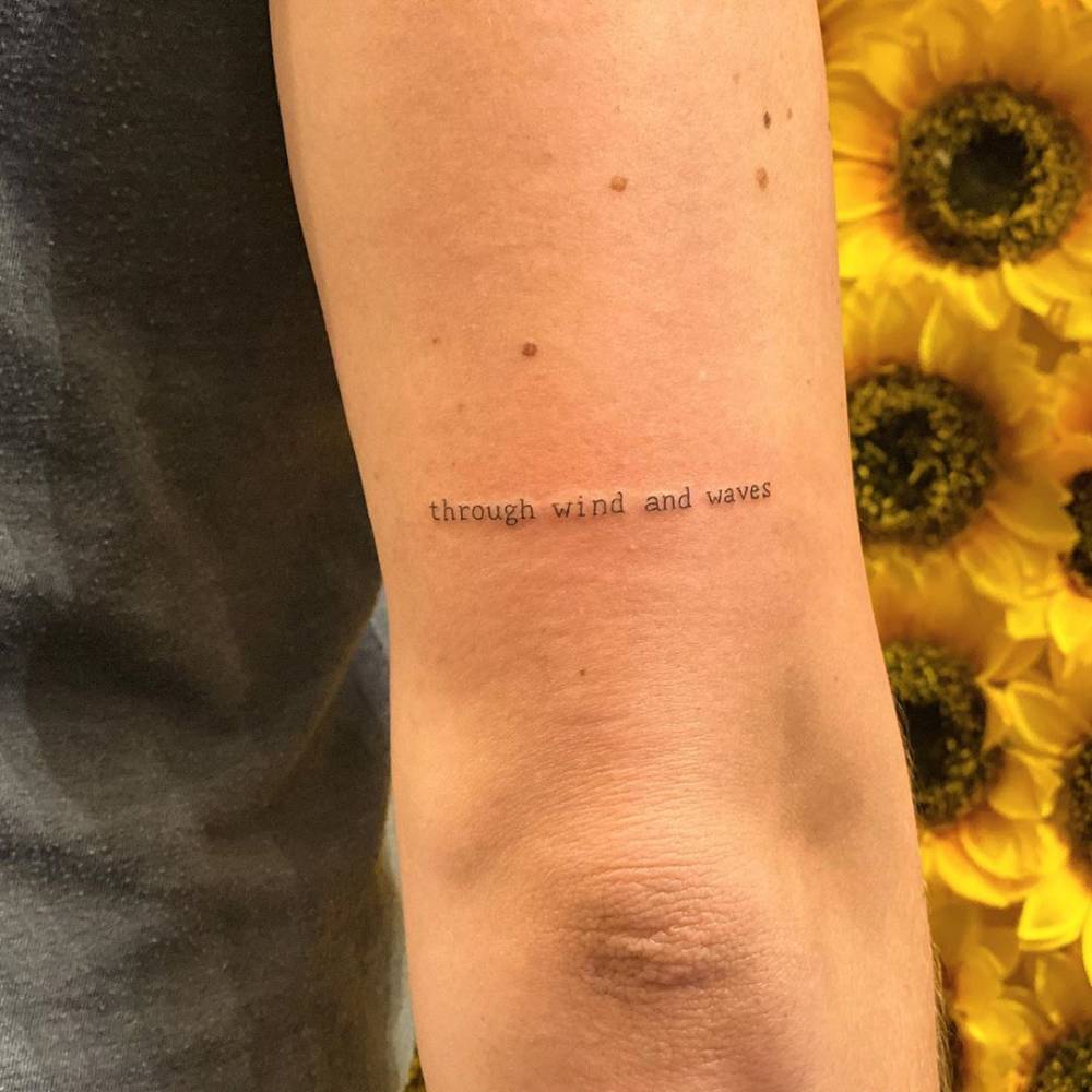 "Through wind and waves" lettering tattoo located on the tricep.