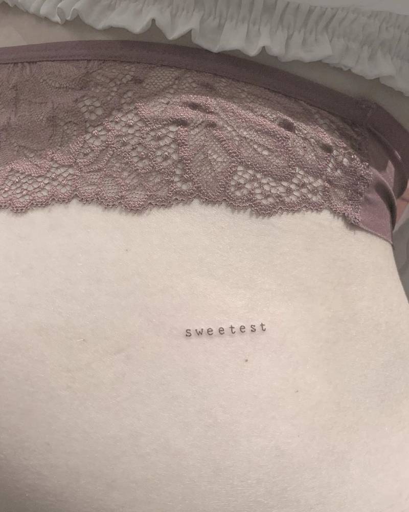 Typewriter font word "sweetest" tattooed on the butt cheek.
