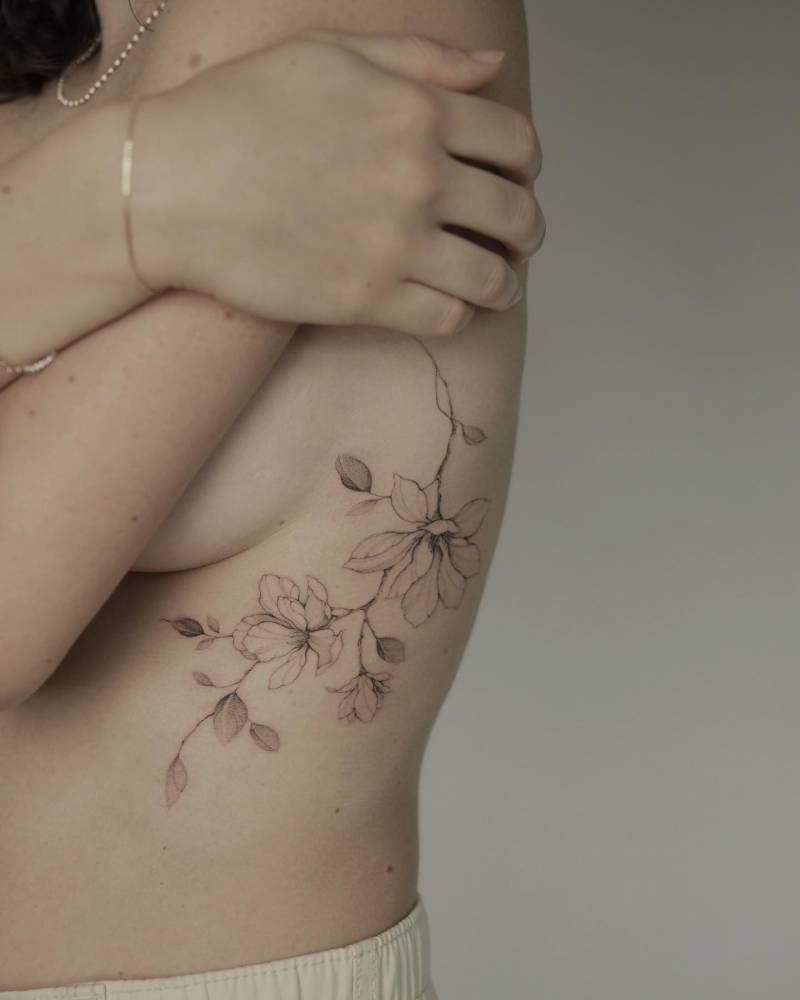 Illustrative style magnolias tattoo located on the rib.