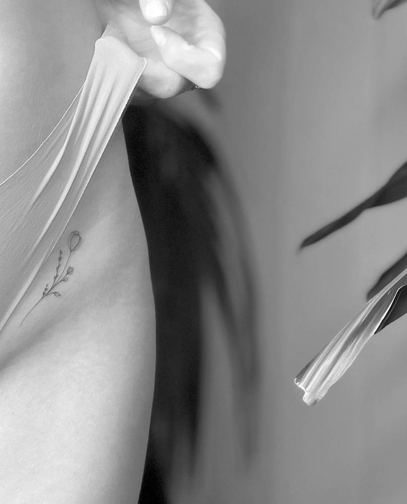 Flower tattoo located on the pelvis, illustrative style.