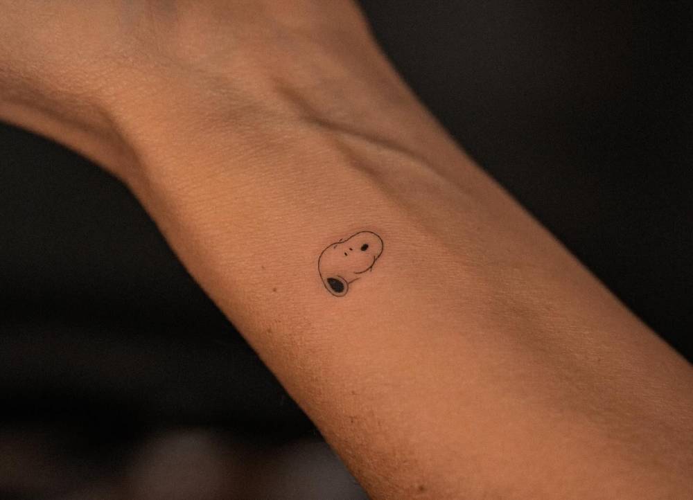 Minimalistic style Snoopy portrait tattoo done on the wrist.