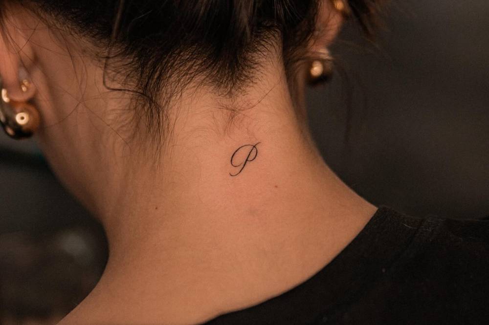 Little tattoo of the letter "P" located on the back of the neck.