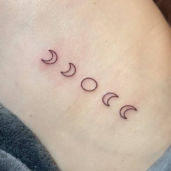 Minimalistic style moon phases tattoo done on the rib.