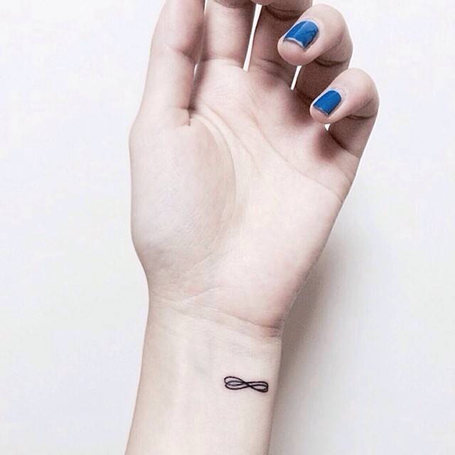 Infinity symbol tattoo located on the wrist, done in minimalistic style.