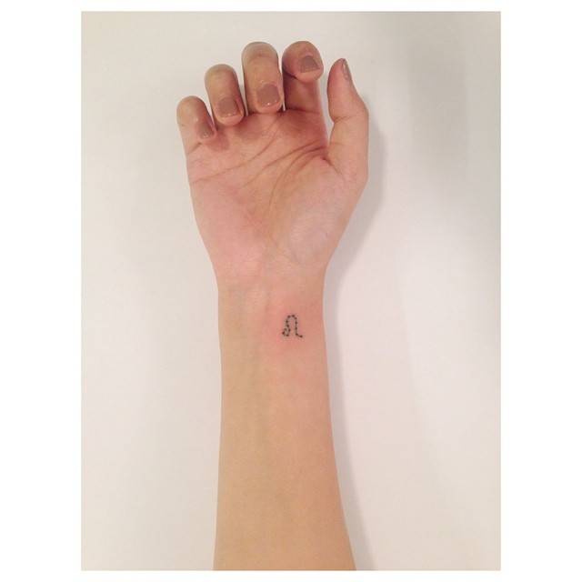 Leo zodiac symbol in minimalistic style tattooed on the wrist.