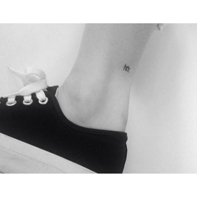 Tiny lettering tattoo of the word "her" located on the ankle.