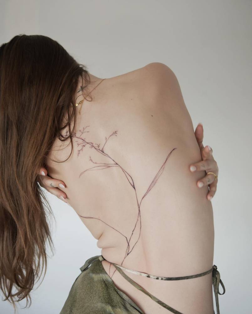 Grass tattoo in illustrative style located on the back.