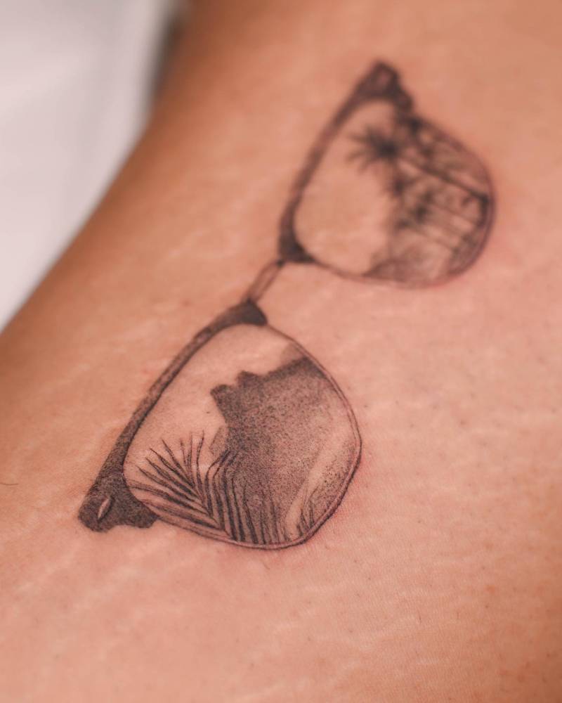 Reflecting glasses tattoo located on the inner arm.