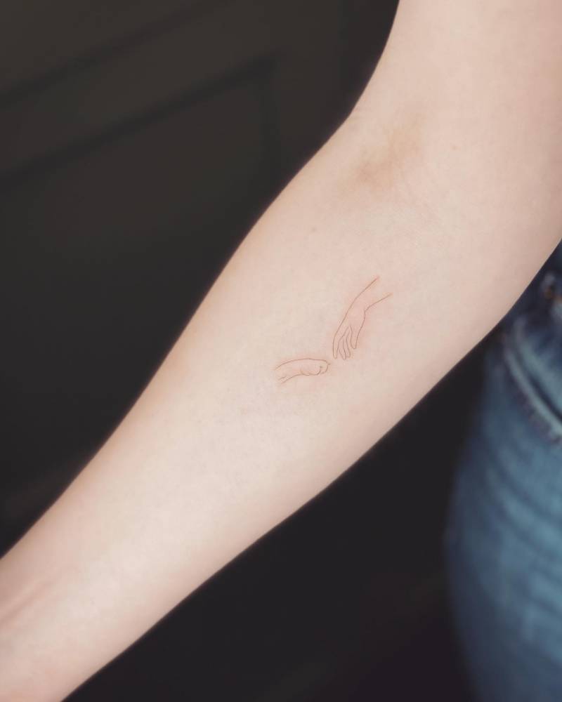 Minimalistic hand and paw tattoo located on the inner forearm.