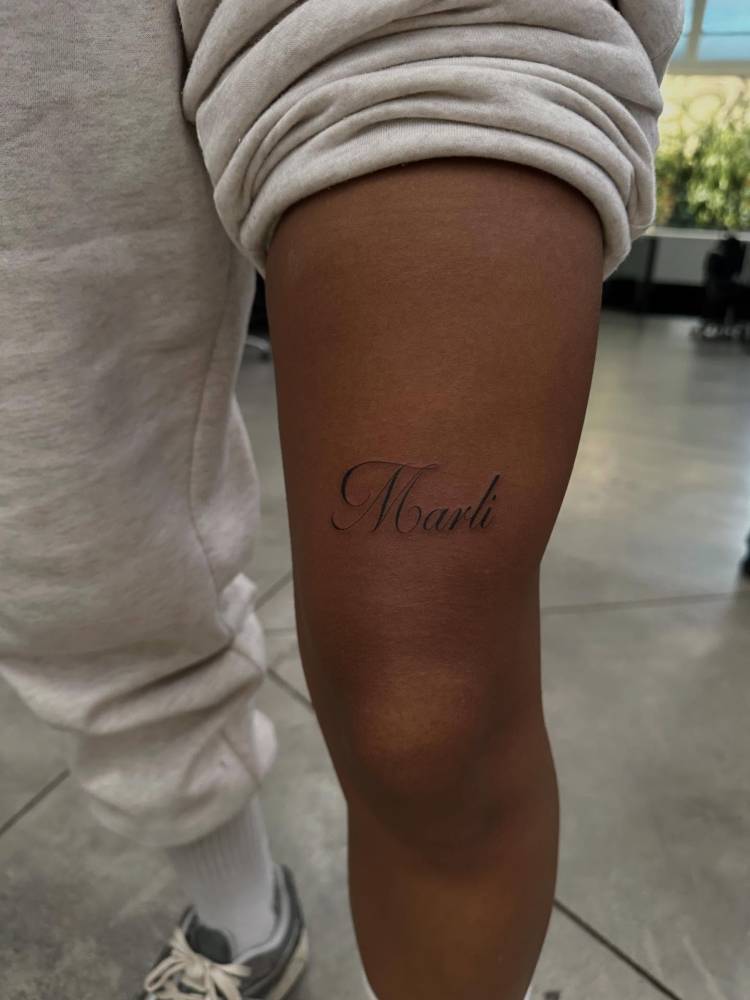 "Marli" lettering tattoo located on the thigh.