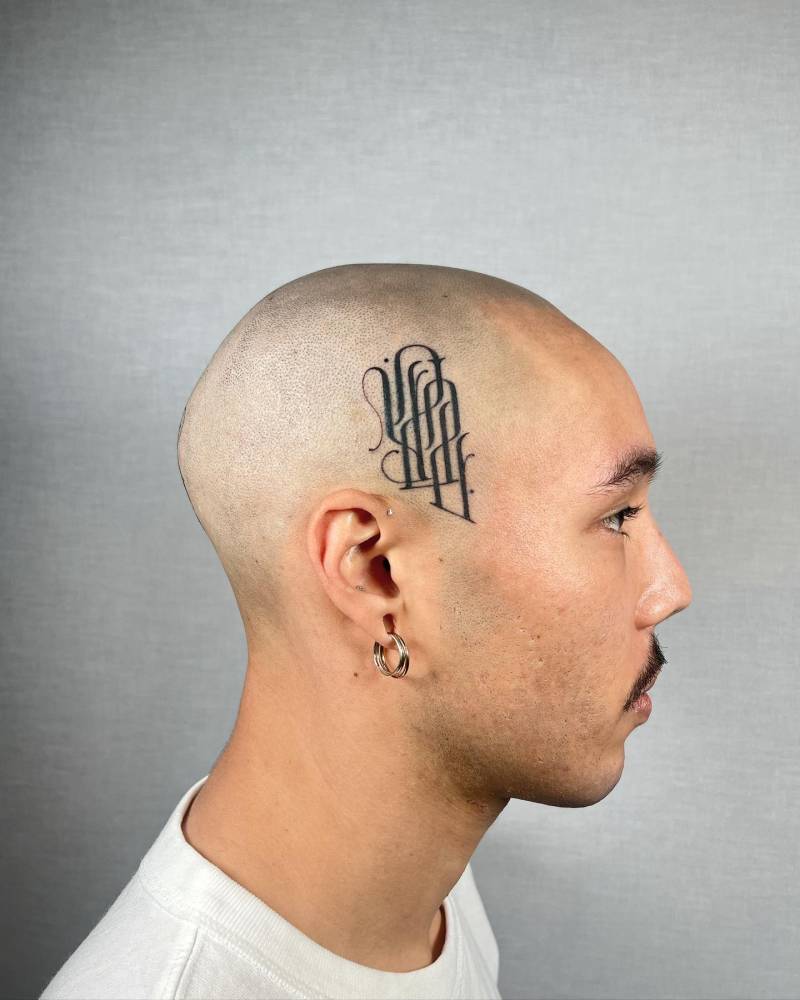 Monogram tattoo located on the side of the head.