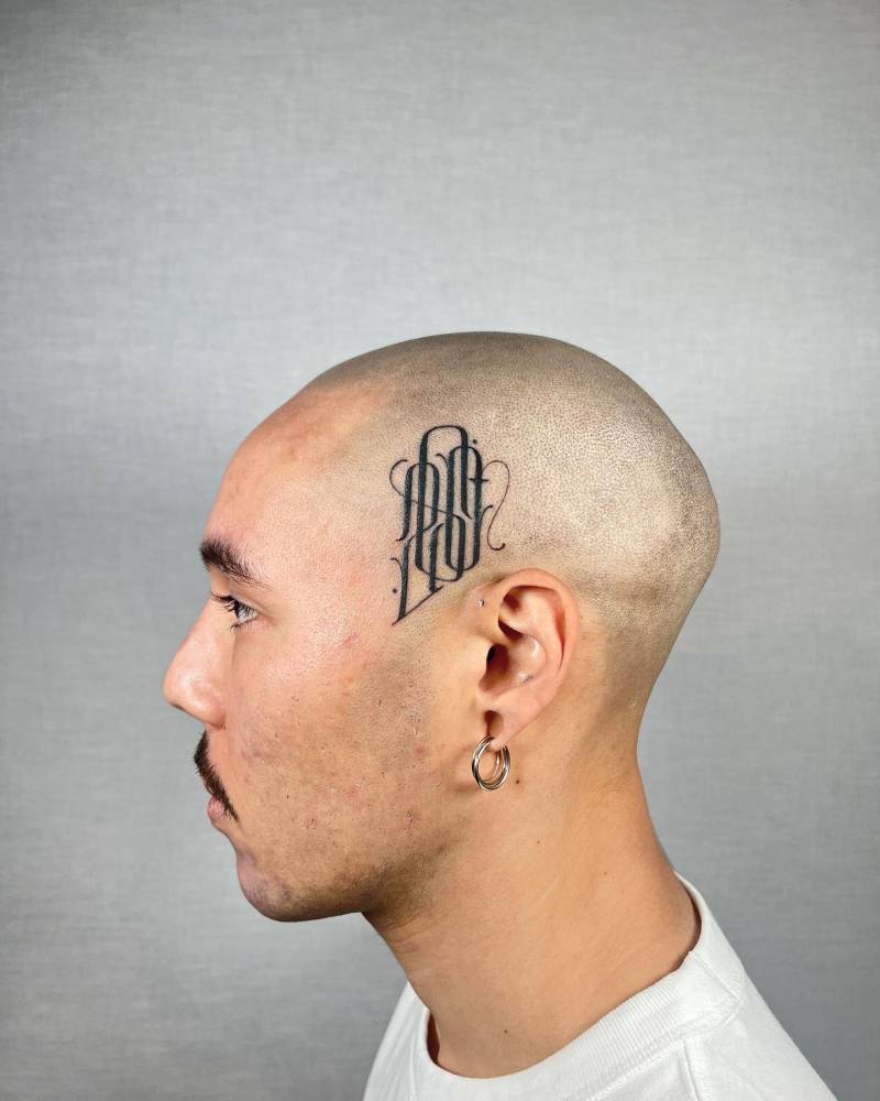 Monogram tattoo located on the side of the head.