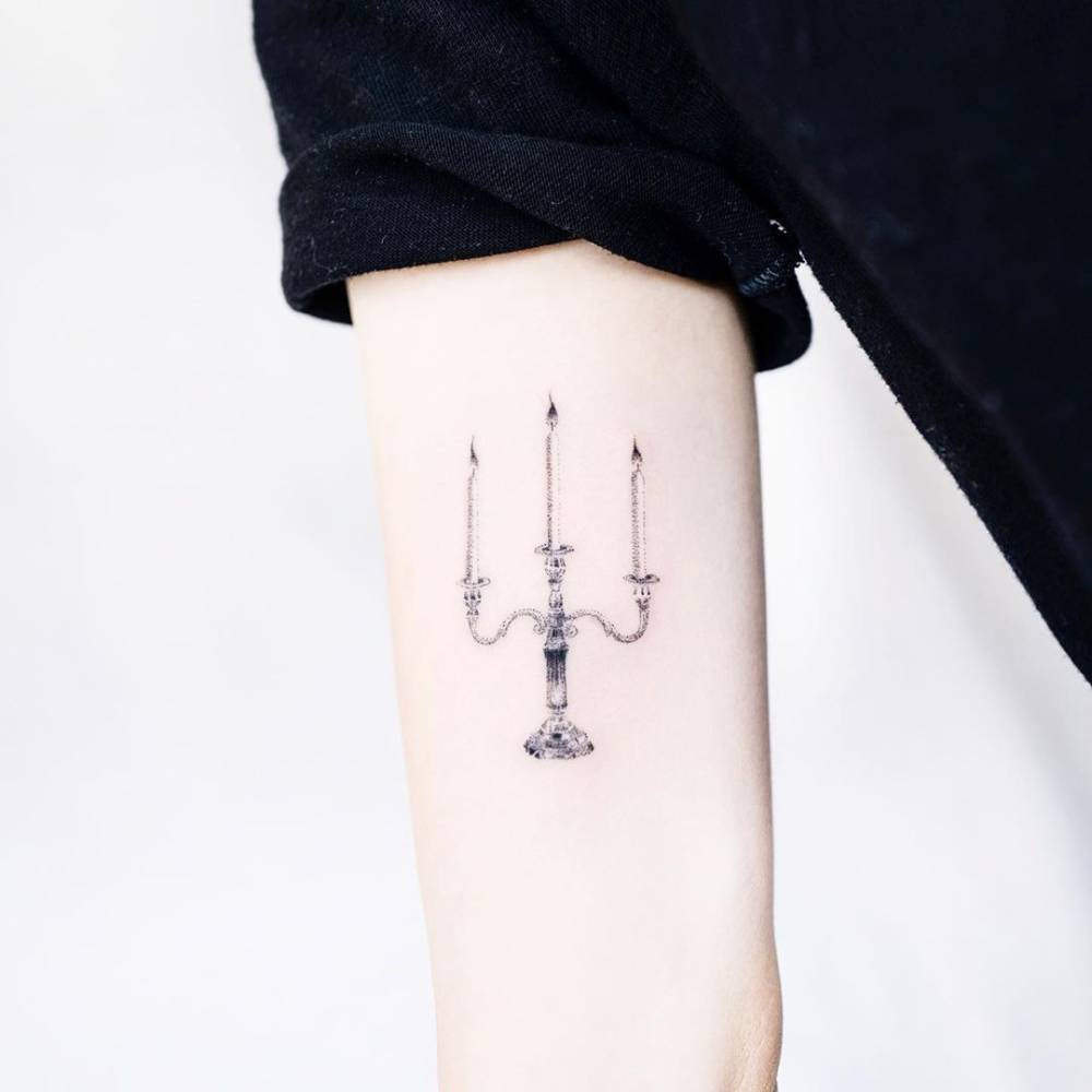 Micro-realistic style candelabra tattoo located on the inner arm.