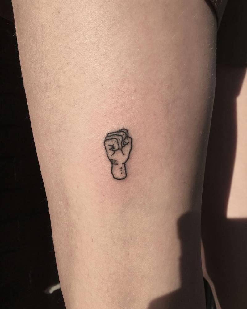 Hand poked little fist tattoo located on the thigh.