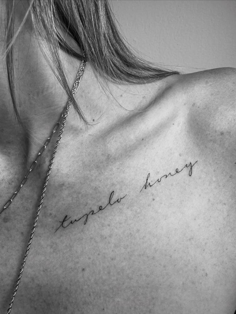 "Tupelo honey" lettering tattoo located on the collarbone.