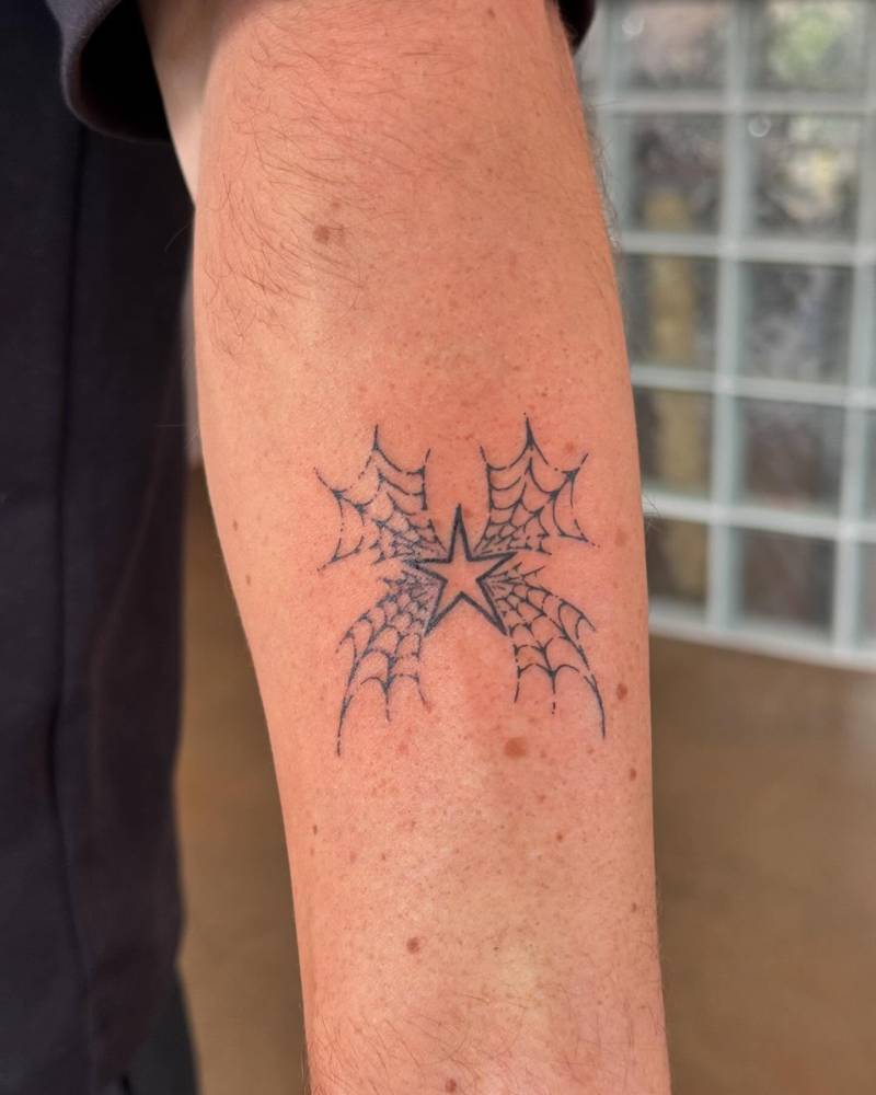 Star and spiderwebs tattoo located on the forearm.