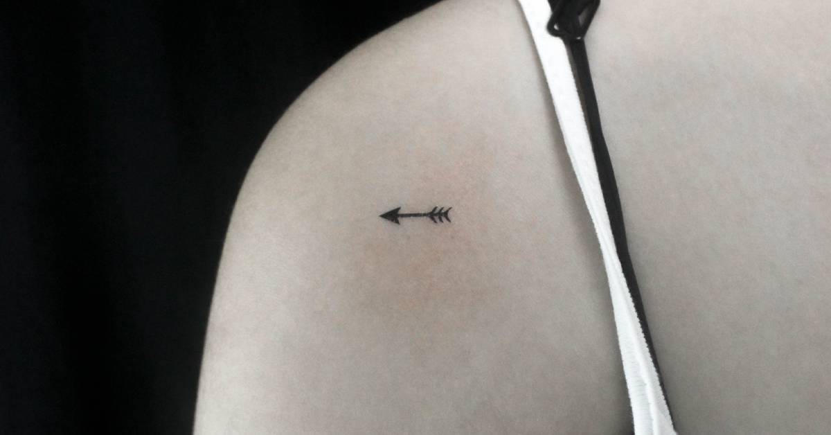 Tiny arrow temporary tattoo located on the shoulder.