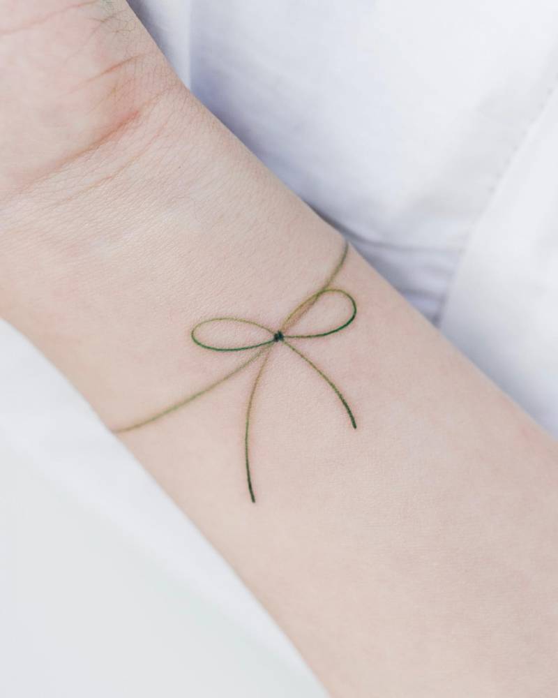 Ribbon wristband tattoo done in fine line style.