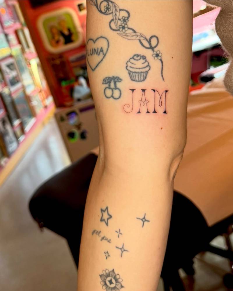 Lettering tattoo of the word "jam" located on the inner arm.