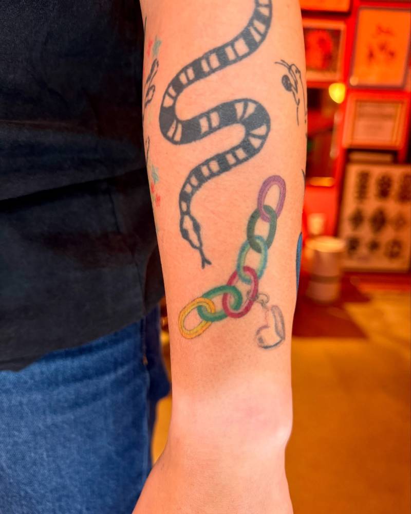 Healed colorful chain tattoo located on the forearm.