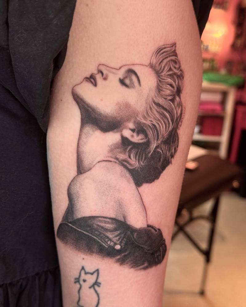 Black and grey style Madonna portrait tattoo located on the thigh.