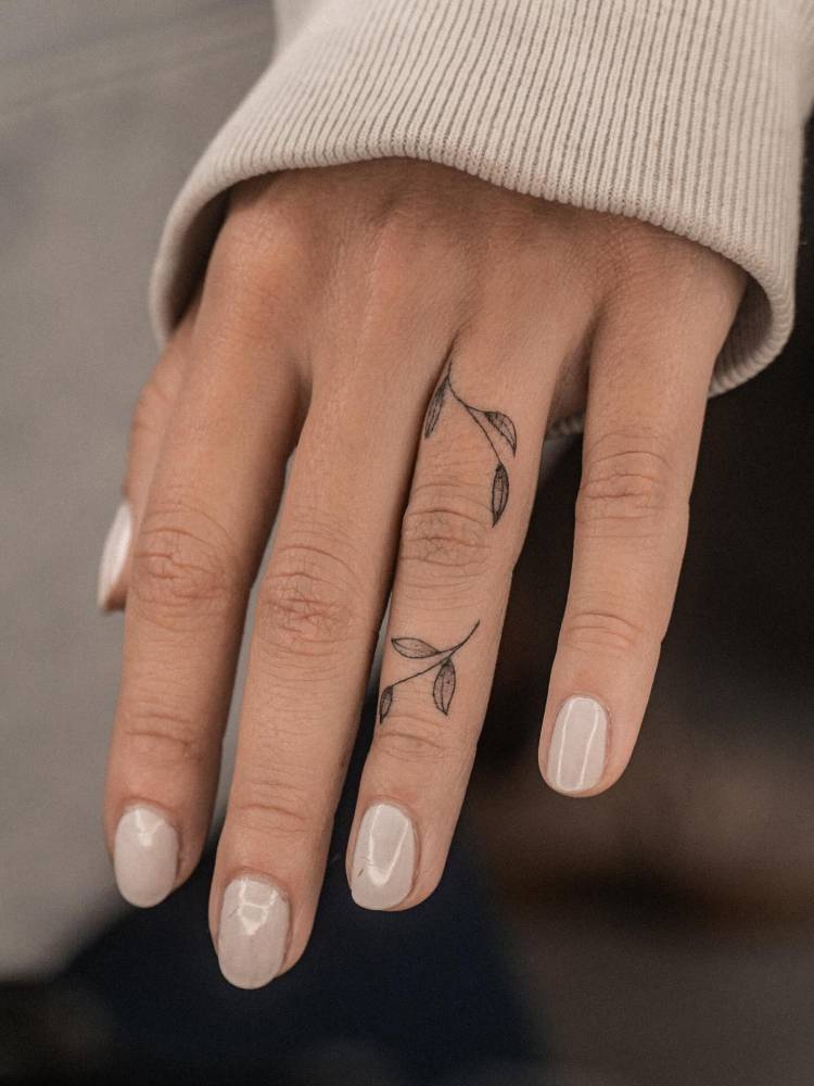 Tiny leaves tattoo in minimalistic style placed on the finger.