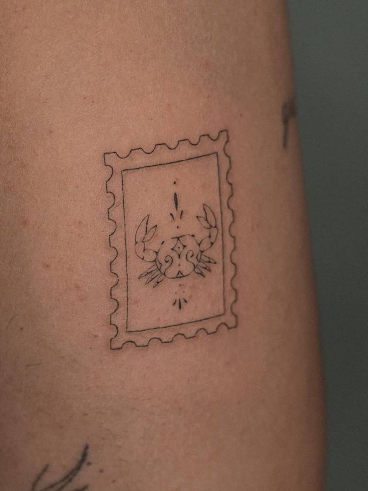 Ornamental crab stamp tattooed on the tricep.