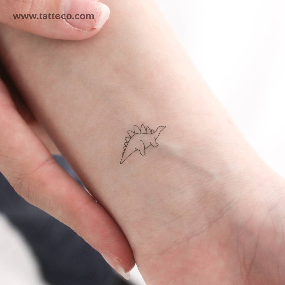 Tiny minimalist stegosaurus temporary tattoo located on the wrist.