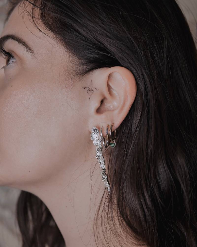 Fine line style ornament tattoo located on the ear.