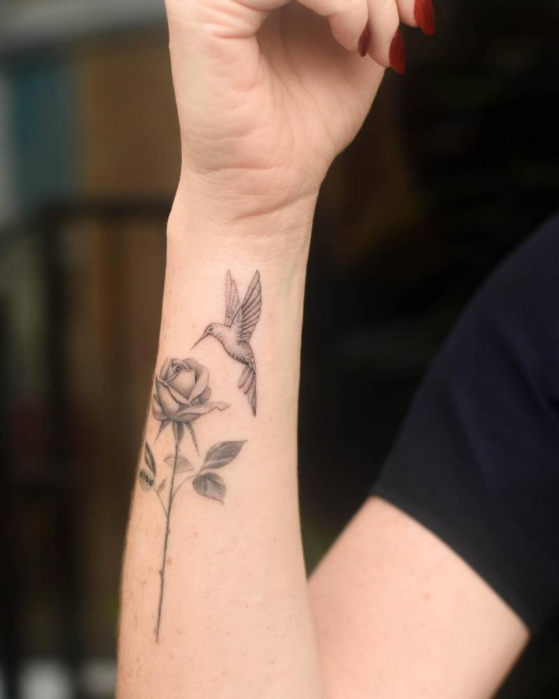 Micro-realistic style rose and hummingbird tattoo located on the forearm.