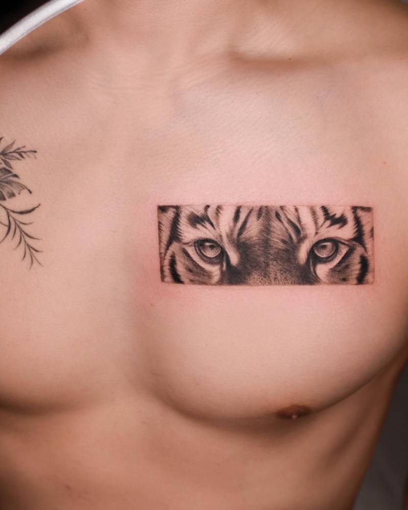 Black and grey tiger eye tattoo located on the chest.